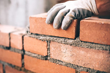 Close up of industrial bricklayer installing bricks on construction site